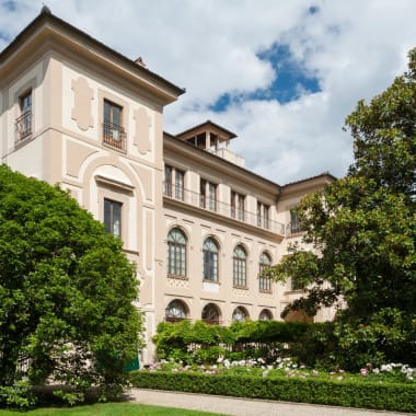 Elegantes mehrstöckiges Hotelfassade mit klassischer Architektur, umgeben von üppigen grünen Bäumen und einem gepflegten Garten.