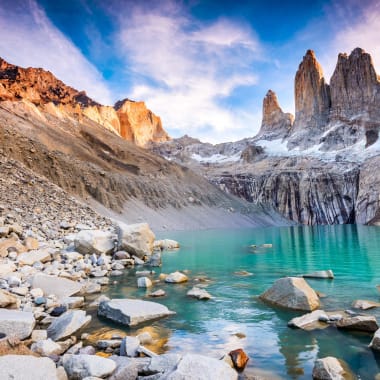 Ein ruhiger türkisfarbener See, umgeben von zerklüfteten Berggipfeln und felsigen Ufern in Patagonien.