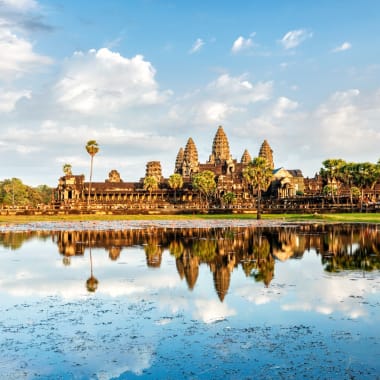 Angkor Wat Tempelkomplex spiegelt sich in einem großen Teich mit blauem Himmel und vereinzelten Wolken.