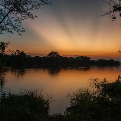 Sonnenaufgang ueber einem See im Lake Mburo Nationalpark