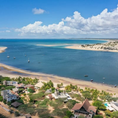 Aerial view of Lamu Island with a river, sandy beaches, and a small town with houses and boats.