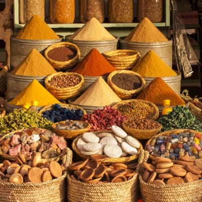 Colorful spices and herbs arranged in baskets at a market stall in Marrakesh, Morocco.