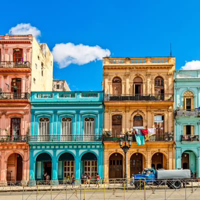 Colorful buildings in Havana, Cuba, with vibrant facades and laundry hanging outside under a bright blue sky.