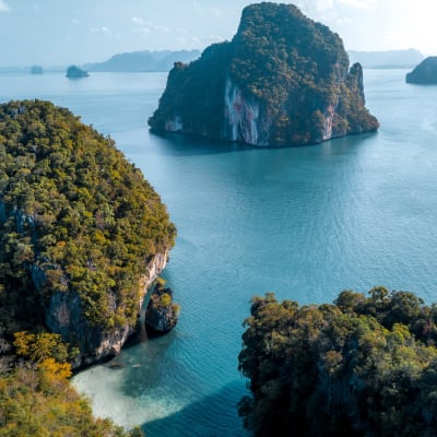 A scenic view of limestone islands covered with greenery surrounded by calm blue waters.