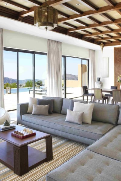 Geräumiges Wohnzimmer mit großen Glastüren, die zu einer Terrasse mit Bergblick führen, mit modernen Sofas, einem Holztisch und eleganter Dekoration.