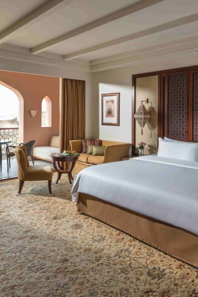 Luxuriöses Hotelzimmer mit großem Bett, Sitzbereich und Balkon mit Aussicht.