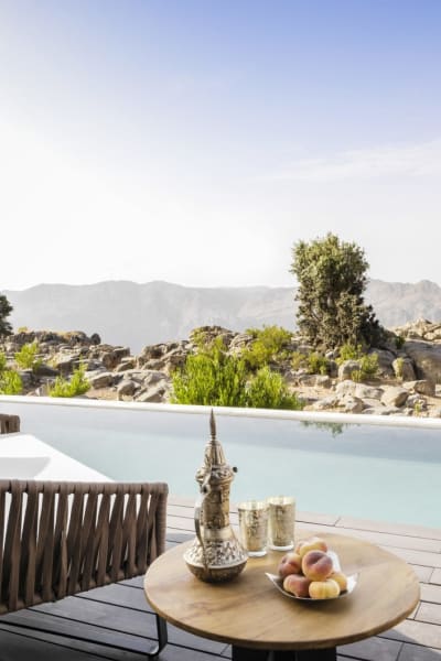 Eine luxuriöse Villa Terrasse mit einem privaten Pool mit Blick auf eine felsige Wüstenlandschaft mit spärlicher Vegetation.