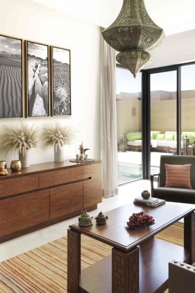 Wohnzimmer mit modernem Mobiliar und großen Glastüren, die zu einer Terrasse im Freien mit Sitzgelegenheiten führen, in einem luxuriösen Resort.