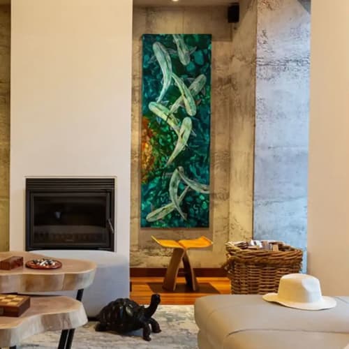 Gemütliches Wohnzimmer mit modernen weißen Sesseln, mehrstöckigen Holztischen, Kamin, lebendiger fischmotivierter Wandkunst und einer schwarzen Katze, die auf einem Teppich liegt.