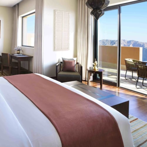 Luxuriöses Hotelzimmer mit Kingsize-Bett, Sitzecke und Balkon mit Blick auf die Berge.