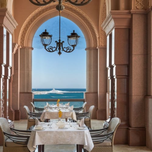 Eine luxuriöse Restaurantterrasse mit Blick auf das Meer, mit eleganten Tischen und traditioneller Architektur.