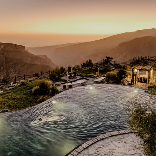 Luxuriöser Infinity-Pool mit Blick auf die bergige Landschaft bei Sonnenuntergang im Alila Jabal Akhdar
