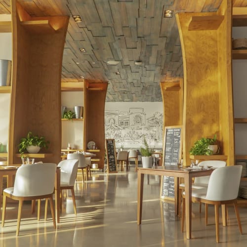 Elegant restaurant interior with white chairs, wooden tables, and decorative shelves filled with ceramics and plants.