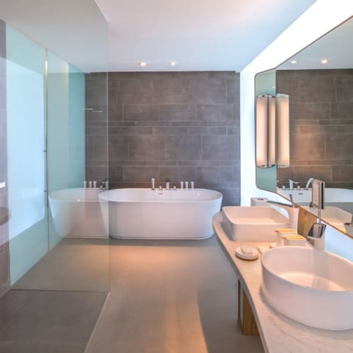 Luxuriöses Badezimmer mit moderner Badewanne und Doppelwaschbecken, mit eleganten Designelementen und großen Spiegeln.