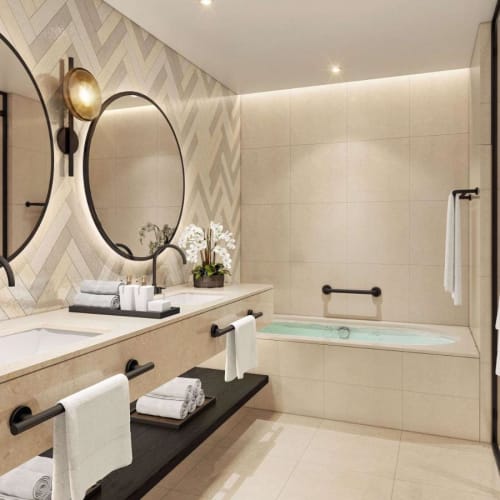 Ein modernes Badezimmer mit zwei großen runden Spiegeln, integrierter Badewanne und schwarzen Armaturen, in neutralen Tönen dekoriert.