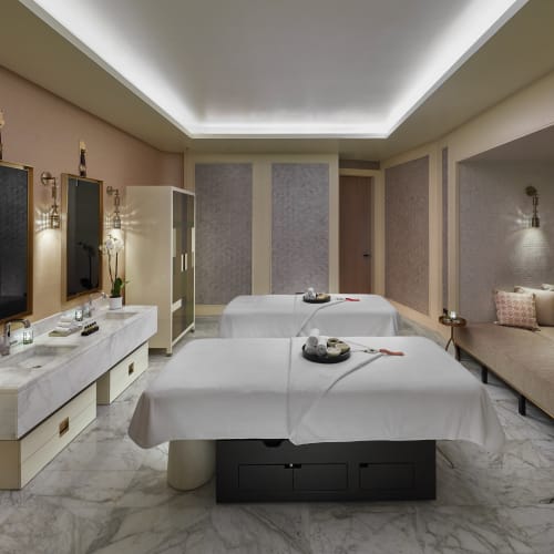 Zwei Massagebetten in einem luxuriösen Spa-Raum mit sanfter Beleuchtung und elegantem Dekor.