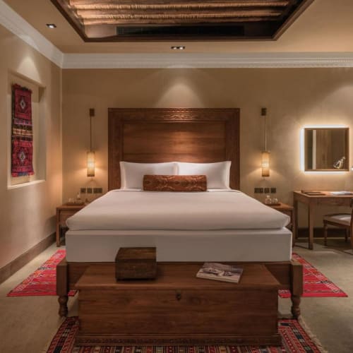 Elegantes Hotelzimmer mit warmer Beleuchtung, Holzmöbeln und traditioneller Wandkunst.