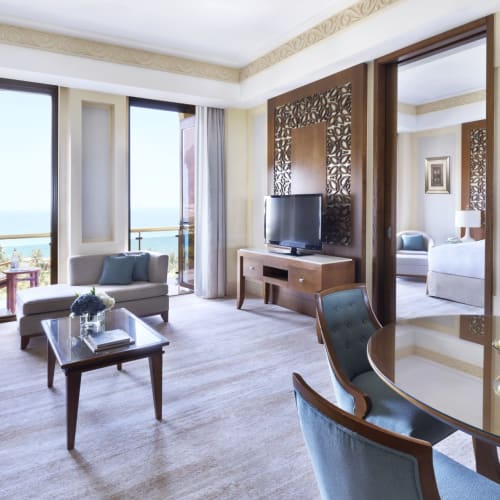 Luxuriöses Hotelwohnzimmer mit großen Fenstern, Meeresblick und eleganter Einrichtung in Oman.