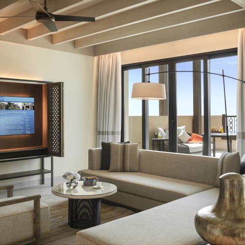 Luxuriöses Wohnzimmer mit modernem Mobiliar und großem Fenster, das einen Sitzbereich im Freien zeigt