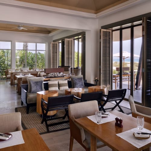 Elegant dining area with large windows, outdoor seating with umbrellas, and a mix of modern and traditional furniture.