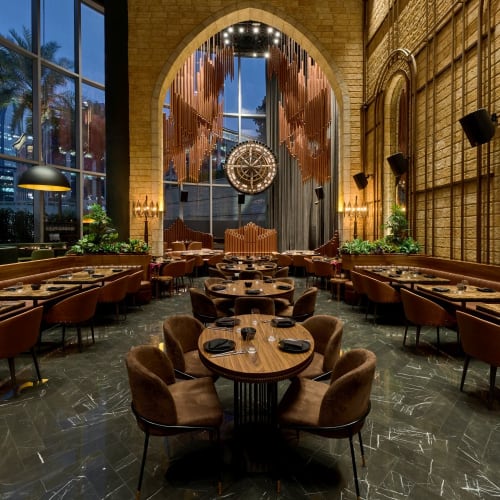 Elegantes Restaurantinterior mit großen Fenstern, warmem Licht und stilvoller Dekoration.