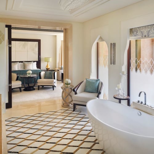 Luxurious hotel room with a freestanding bathtub near a large window overlooking the outside.