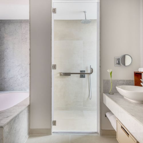 A modern bathroom with a bathtub on the left, a glass shower in the center, and a double sink vanity on the right.