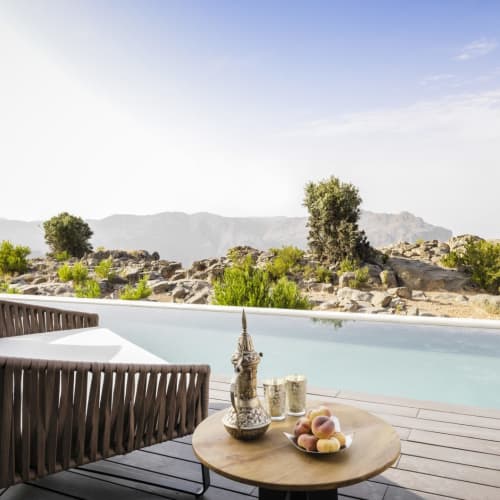 A luxurious villa terrace with a private pool overlooking a rocky desert landscape with sparse greenery.