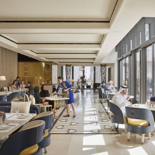 Luxuriöse Speisebereich mit eleganten Möbeln, großen Fenstern und Gästen beim Essen.