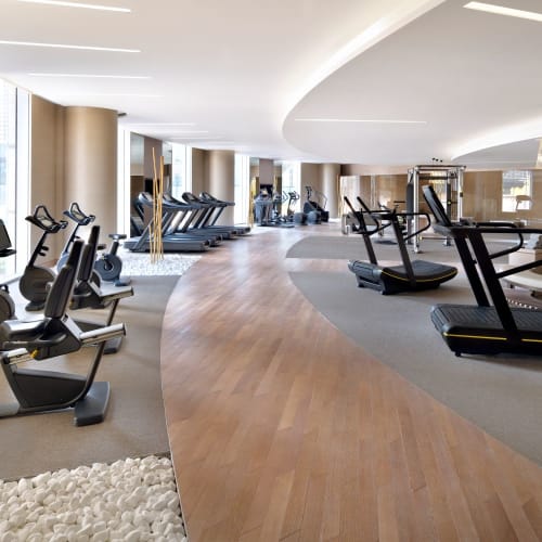 Geräumiges modernes Fitnessstudio mit Cardio-Geräten einschließlich Laufbänder und stationäre Fahrräder, und einem geschwungenen Holzbodenweg.