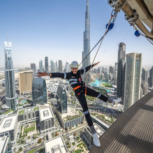 Eine Person genießt eine aufregende Zipline-Fahrt hoch über Dubai mit der Skyline im Hintergrund.