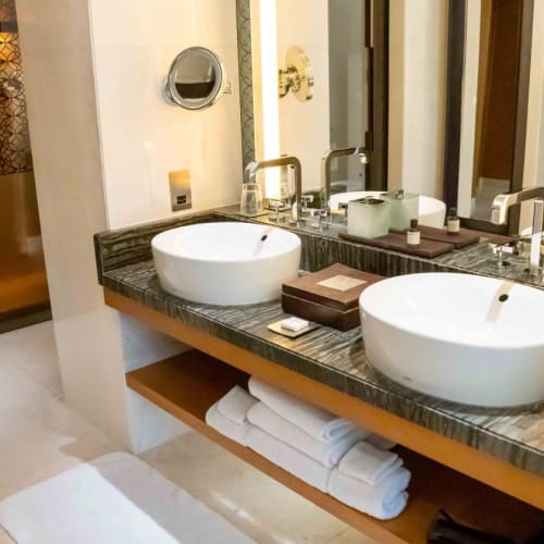 Luxurious bathroom with two round white vessel sinks on a dark marble countertop and a large mirror.