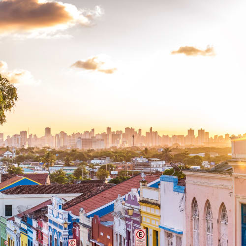 Bunte historische Gebäude in Olinda mit Sonnenuntergang und Stadtansicht im Hintergrund.