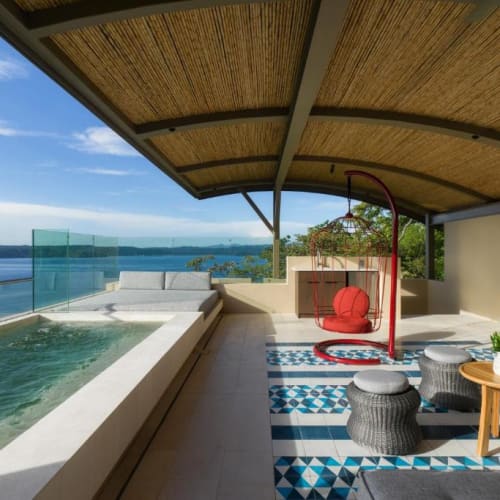 Eine geräumige Veranda im Freien mit einem privaten Pool, Sitzbereich und Blick auf Wasser und Himmel.