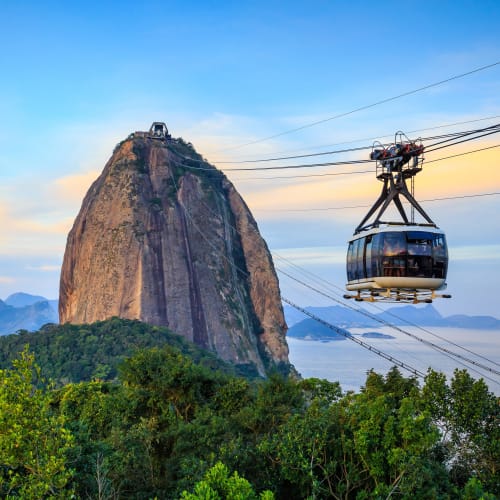 A cable car suspends in the sky with Sugarloaf Mountain in the background in Rio de Janeiro, Brazil.