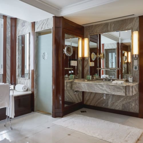 Luxuriöses Badezimmer mit Marmorflächen, großem Spiegel und moderner Beleuchtung in einer stilvollen Hotel-Suite.