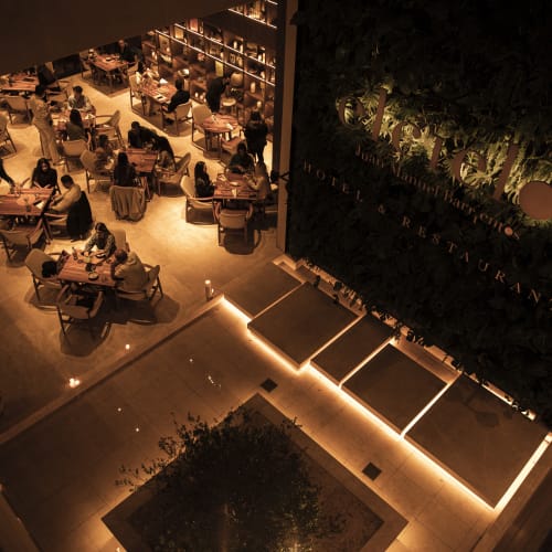 Schwach beleuchtetes Restaurant mit mehreren Tischen, an denen Gäste sitzen, warme Ambientebeleuchtung schafft eine gemütliche Atmosphäre.
