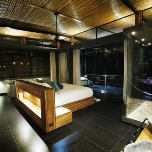 Luxurious villa bedroom with an adjoining open-air bathroom featuring stone sinks and modern fixtures at Kura Boutique Hotel, Uvita, Costa Rica.