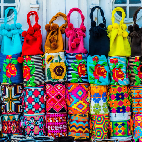 Bunte handgewebte Taschen und bestickte Accessoires im Freien displayt.
