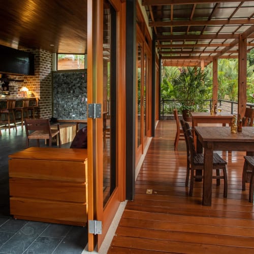 Innenbereich der Bar verbunden mit einer outdoor Holzterrasse mit Tischen, umgeben von üppigem Grün in Costa Rica.