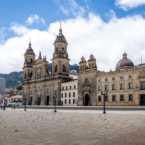 Ein Blick auf den Bolivarplatz in Bogotá mit kolonialartiger Architektur und einem großen offenen Platz unter einem wolkigen Himmel.