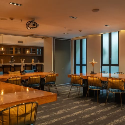 Innenraum einer modernen Bar mit Holztischen und Metallstühlen mit Kissen, beleuchtet durch warmes Licht und dekorative, sternförmige Lampen auf den Tischen.
