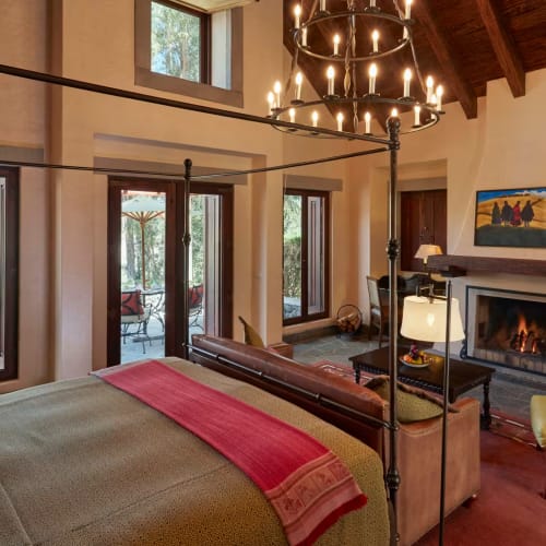 Luxuriöses Schlafzimmer mit großen Fenstern, Kamin und eleganten Möbeln in einem Raum mit hohem Decken.