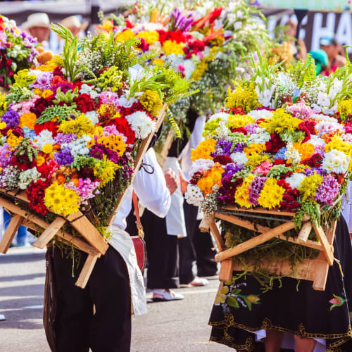 Menschen tragen große Sträuße mit bunten tropischen Blumen bei einer Parade oder Feier in Kolumbien.