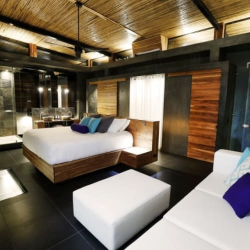 Luxurious villa bedroom with a spacious bed, white sofa, and elegant interior design in Uvita, Costa Rica.