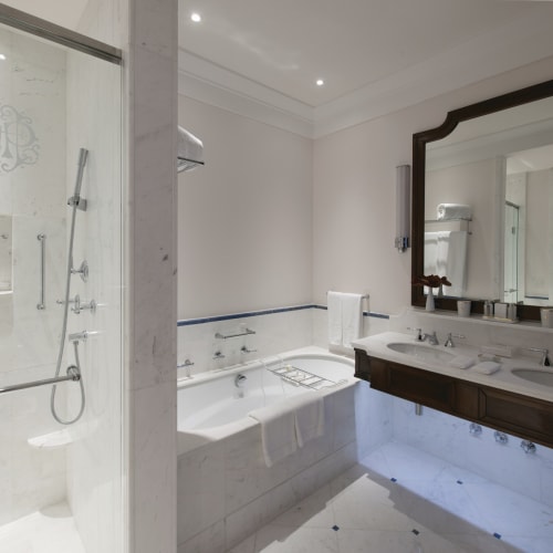 Luxuriöses Badezimmer mit begehbarer Dusche und großem Spiegelschrank in einem exklusiven Hotel.