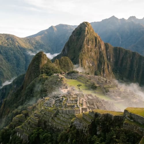 Antike Machu Picchu Ruinen eingebettet zwischen grünen Bergen mit Nebel in den Tälern am Tag.