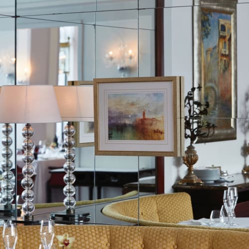 Elegantes Restaurantinnenraum mit Lampen, eingerahmten Gemälden und dekorativen Kerzenleuchtern in einem luxuriösen Ambiente.