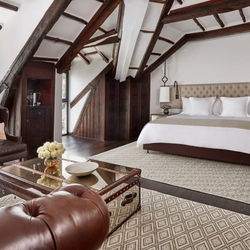 Luxuriöses Schlafzimmer mit einer gewölbten Decke, weißem Bett und dunklen Holzakzenten in einem Hotelzimmer.
