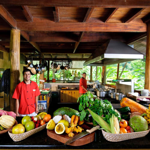 The open kitchen of Pacuare Lodge with chefs preparing fresh fruit and vegetables.